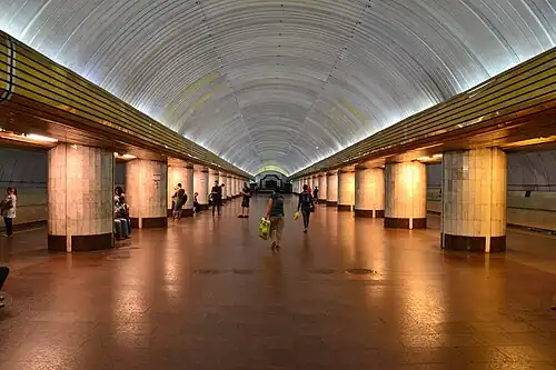 Underground station with a brown floor and white columns and ceiling