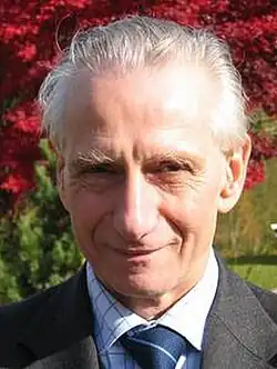 Headshot of Doplicher smiling in front of a flower garden