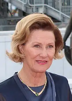 Crown Princess Sonja outdoors, dressed in dark blue, with a gold necklace.