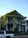 Dilapidated wooden house overgrown with cat's claw vine