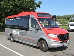 Grey and red Mercedes-Benz minibus with white text along its side reading 'fflecsi Dyffryn Conwy/Conwy Valley'