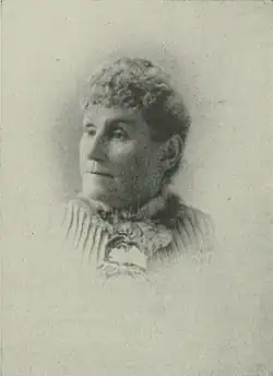 19th-century B&W portrait photo of a woman with her hair in an up-do, wearing a dark, fitted blouse.