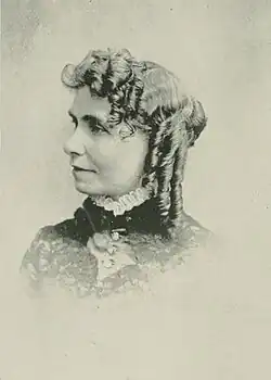 19th-century B&W portrait photo of a woman with her hair in an up-do, wearing a dark, fitted blouse.