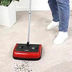 Someone using a carpet sweeper to clean up debris