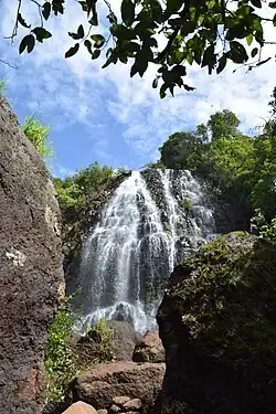 Two-tier monsoon waterfall amid lateritic rock and greenery