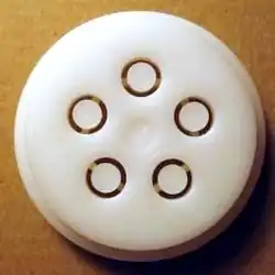 Front view of a circular plastic pasta extrusion die with five small tubular openings
