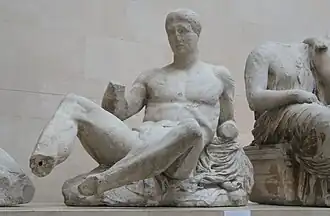 Greek sculpture, showing a reclining male figure, with hands and feet broken off and face badly weathered