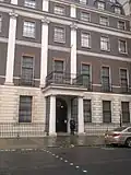 A policeman outside the embassy; the National Emblem of China can be seen above the door