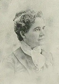 19th-century B&W portrait photo of a woman with her hair in an up-do, wearing a dark, fitted blouse.
