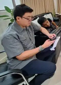 A man sitting on a chair is using a cellphone