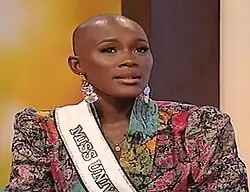 Photograph of Engracia Mofuman with a white Miss Universe sash