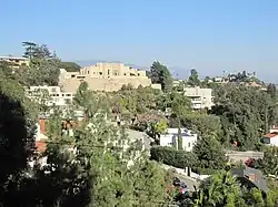 View of the Ennis House from another building. There are several houses between the Ennis House and the photographer's location, positioned at a lower elevation than the Ennis House.