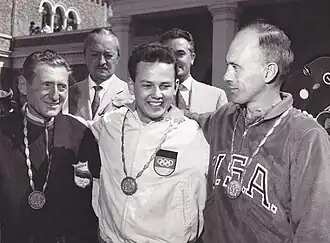 Black and white photograph of three men, wearing Olympic medals.