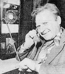 Portrait of Erwin Kreuz. Herr Kreuz was a brewery worker from Adelsreid, Germany; the photograph is a black-and-white one published in newspapers during his trip to the United States in 1977; he is shown on the telephone and smiling at the camera.