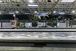 Interior of a metro station with two parallel platforms separated by train tracks.