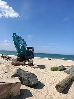 Excavator performing coastal maintenance and debris clearing at Stockton Beach