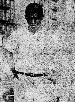Black-and-white mid-length photograph of Saitch staring straight ahead