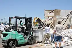 A supermarket having its debris cleared out by volunteers with a forklift