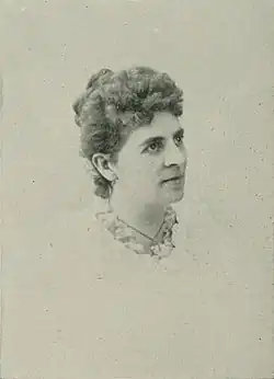 B&W portrait photo of a middle-aged woman wearing a pale, high-collared blouse with her hair in an up-do.