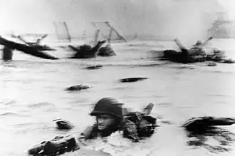A blurry picture of an American GI belly crawling through the surf