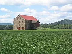 A three-story fieldstone barn with a red roof