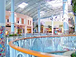 An indoor lake surrounded by colorful storefronts. Many of the storefronts are vacant.