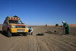 Local touaregs assisting a rally participant with a flat tyre on one of the Moroccan stages of the Budapest-Bamako