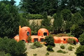 Curved orange domed structure visible from highway bridge, featuring multiple connected dome shapes against hillside