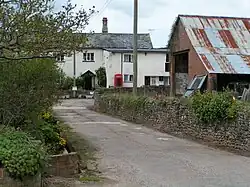 A small paved lane with a short stone wall and small two-story buildings with sloped roofs.