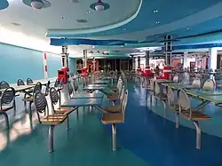 An abandoned food court in Forest Fair Village, featuring blue floors and unused blue tables.
