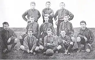 Black and white photograph of 11 men posing with ball