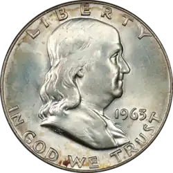 silver coin with man's face painting left on it