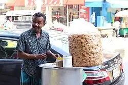 An vendor with panipuri ingredients on a cart along an urban street