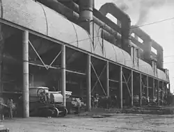Water jacket furnaces, furnace flues and slag wagons (1912). One of the spouts for molten slag is visible to the right of the leftmost column. There is a horse and cart to the right of the third column.