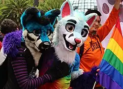 People hugging wearing fursuit heads at a pride parade