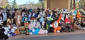 A crowd of people posing for the camera wearing animal costumes (fursuits)