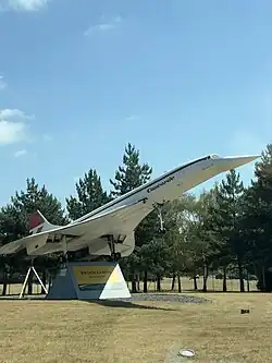 An image depicting a 40% scale model of the Concorde supersonic aircraft with reg. no. G-CONC. The plane is on a stand with its nose facing the sky, almost as if it is taking off. The landing gear is extended.