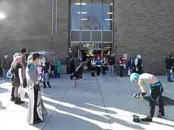 People in costumes watching someone breakdancing in front of a building