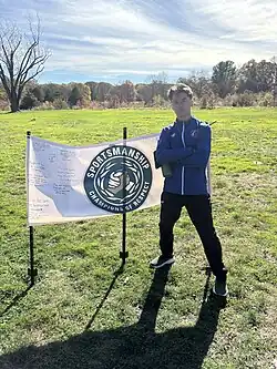 Grant Kellenberger posing with the NEWMAC sportsmanship poster