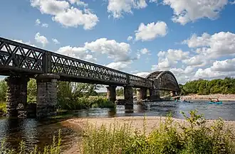 An iron lattice-work viaduct on stone piers crossing a wide river