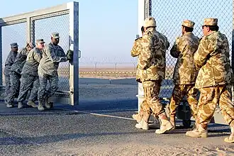Soldiers in beige uniforms closing a gate