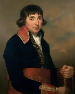 Painting of a man with long dark hair over his ears. He wears a dark blue French military uniform of the 1790s with a red sash around his waist.