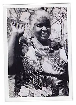 Black and white photo of Georgia Gilmore smiling and waving at the camera with her right hand