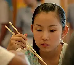 Chinese girl eating with chopsticks