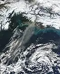 Wind picks up fine sediment from the riverbank and carries it over the ocean.