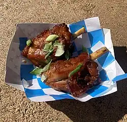 Glazed pork wings with green onion garnish