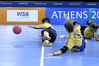 Three men wearing eye shades laying on the floor, a red ball is to the left of the image