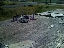 A wooden foundation of a home, clean of debris, with a bicycle on top.