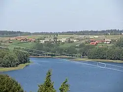Many colorful houses are visible across a lake, separated by power lines in the foreground.