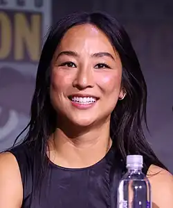 A woman of Korean descent wearing a black top smiles